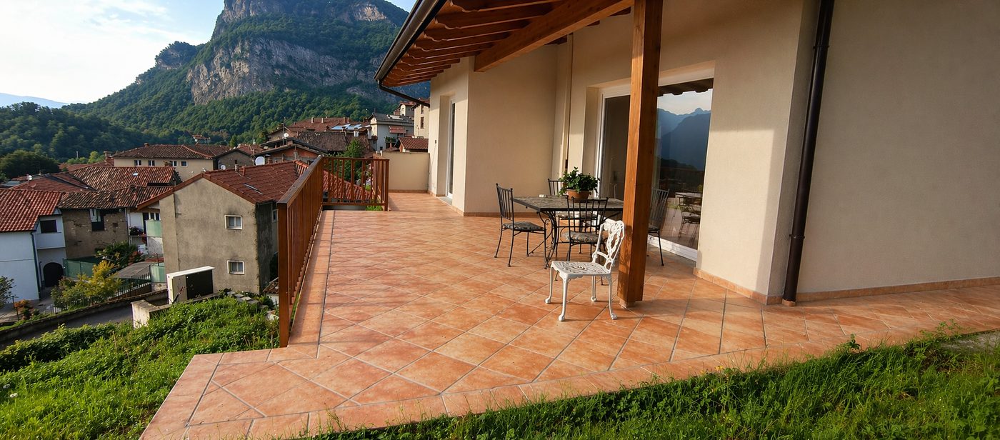 Lo stesso terrazzo nel render con pavimento in cotto e tavolo